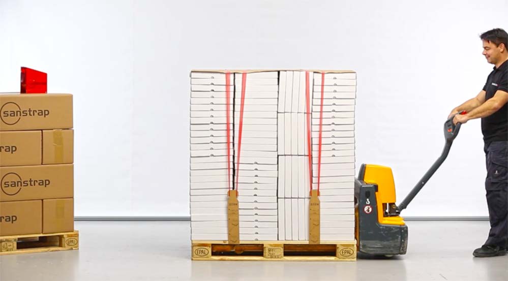 Employee pulls pallet with 2Link® and sanstrap®-secured packaged goods using a pallet truck.

