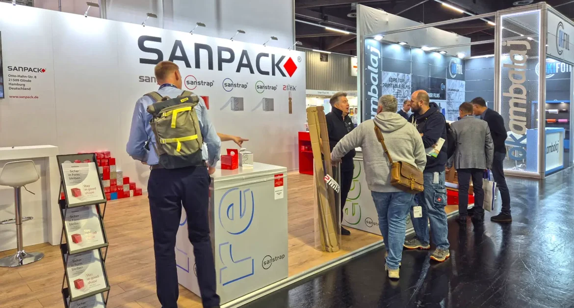 Besucher am Sanpack Messestand auf der Fachpack 2025 informieren sich über sanstrap Dehnbänder zur nachhaltigen Palettensicherung