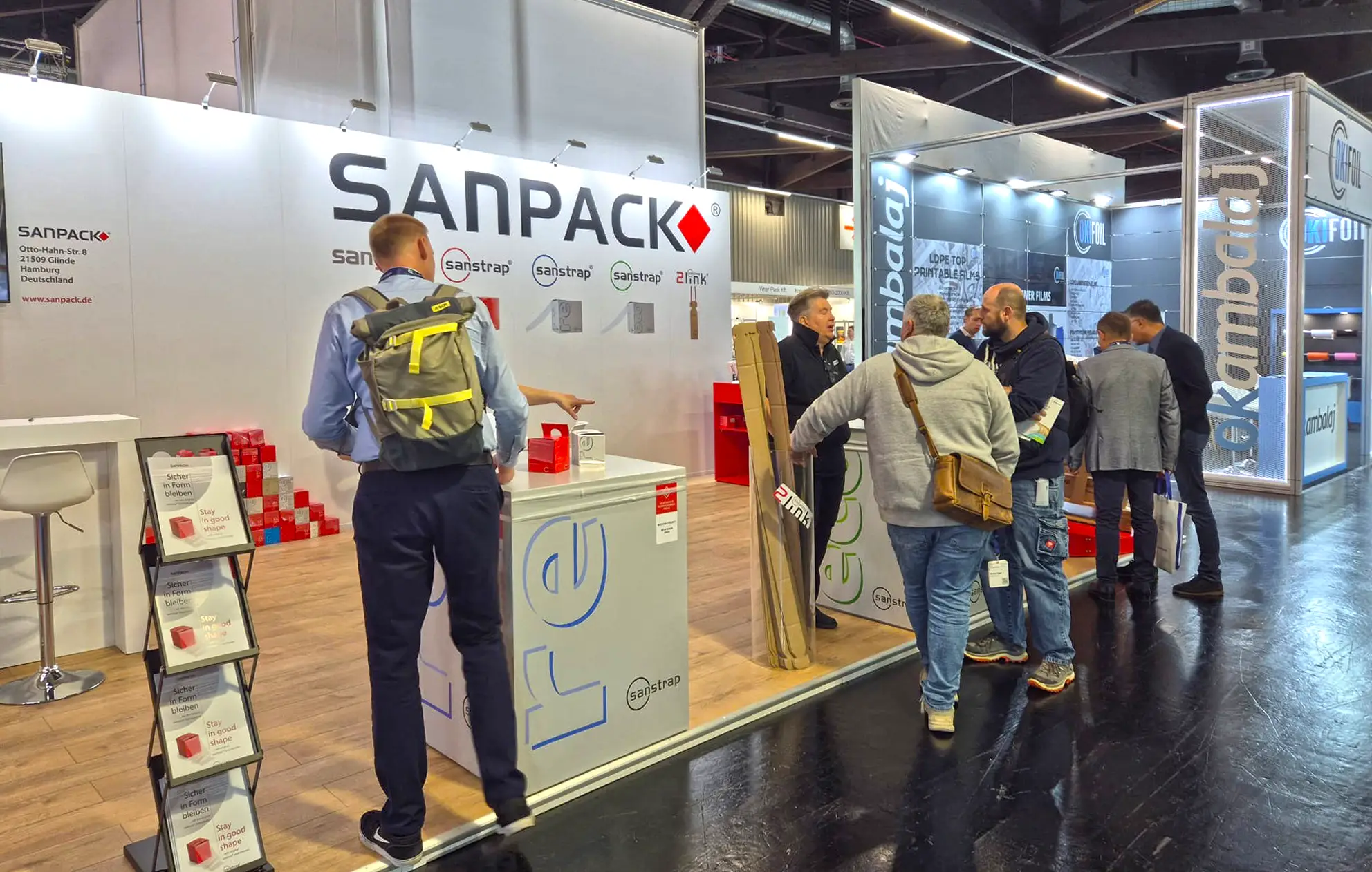 Besucher am Sanpack Messestand auf der Fachpack 2025 informieren sich über sanstrap Dehnbänder zur nachhaltigen Palettensicherung